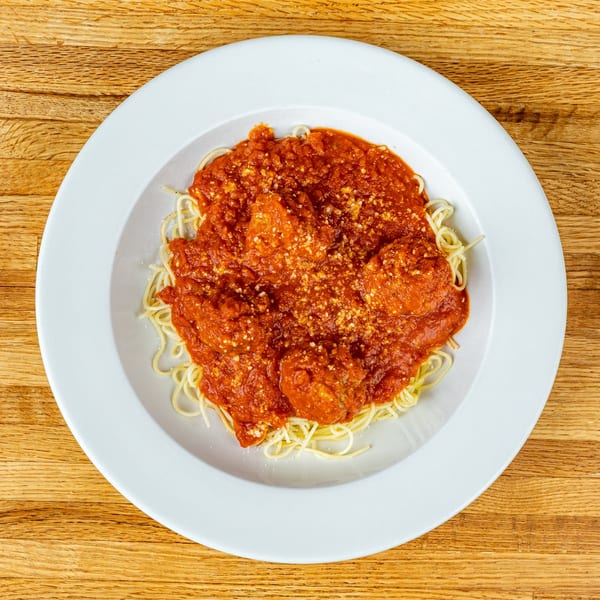 Spaghetti with meatballs and rich red marinara sauce, topped with grated Parmesan cheese, on a white plate.